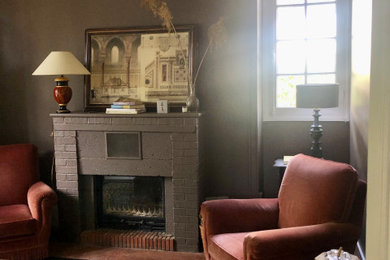 Cette image montre un salon avec une cheminée standard, un manteau de cheminée en brique et un sol rouge.