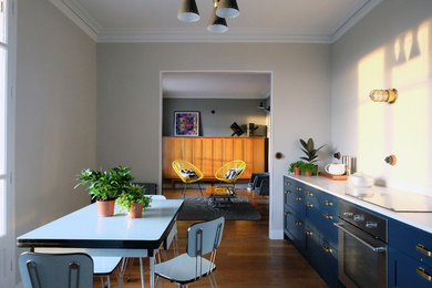 Eat-in kitchen - mid-sized 1950s l-shaped medium tone wood floor eat-in kitchen idea in Paris with a farmhouse sink, shaker cabinets, white cabinets, marble countertops and no island