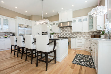 Open concept kitchen - large transitional u-shaped light wood floor open concept kitchen idea in Toronto with an undermount sink, shaker cabinets, white cabinets, granite countertops, multicolored backsplash, glass tile backsplash, stainless steel appliances and an island