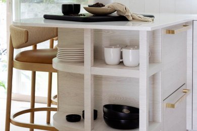 Small trendy l-shaped light wood floor eat-in kitchen photo in Vancouver with flat-panel cabinets, white backsplash and porcelain backsplash