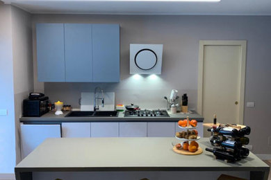 Idee per una cucina minimalista di medie dimensioni con lavello a doppia vasca, ante lisce, ante turchesi, top in laminato, paraspruzzi grigio, elettrodomestici neri, pavimento in cemento, pavimento grigio, top grigio e soffitto ribassato