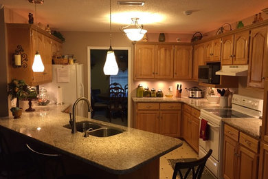 Small elegant u-shaped porcelain tile eat-in kitchen photo in Other with a double-bowl sink, raised-panel cabinets, medium tone wood cabinets, granite countertops, white appliances and a peninsula