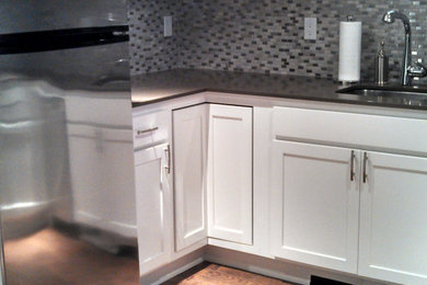 Small transitional l-shaped porcelain tile and brown floor kitchen photo in Seattle with an undermount sink, recessed-panel cabinets, white cabinets, quartz countertops, metallic backsplash, metal backsplash, stainless steel appliances and gray countertops