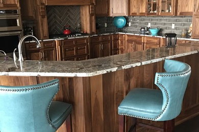 Inspiration for a large transitional u-shaped dark wood floor and brown floor eat-in kitchen remodel in Omaha with shaker cabinets, medium tone wood cabinets, granite countertops, gray backsplash, stone tile backsplash, stainless steel appliances and a peninsula