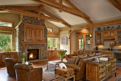 Inspiration for a large timeless medium tone wood floor family room remodel in Denver with beige walls, a standard fireplace, a stone fireplace, a concealed tv and a bar