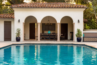 Photo of a mid-sized mediterranean backyard rectangular lap pool in Los Angeles with a pool house and concrete pavers.