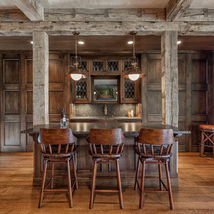 Mittelgroße, Zweizeilige Mediterrane Hausbar mit Bartheke, Unterbauwaschbecken, dunklen Holzschränken, Granit-Arbeitsplatte, braunem Holzboden, verzierten Schränken, bunter Rückwand und braunem Boden in Sonstige