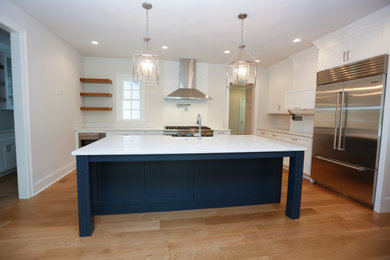 Inspiration for a timeless light wood floor kitchen remodel in Philadelphia with a farmhouse sink, shaker cabinets, white cabinets, quartz countertops and stainless steel appliances