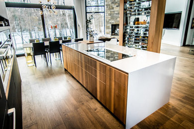 Example of a mid-sized minimalist l-shaped dark wood floor eat-in kitchen design in Montreal with flat-panel cabinets, medium tone wood cabinets, stainless steel appliances and an island