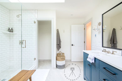 Example of a mid-sized master white tile and subway tile gray floor alcove shower design with recessed-panel cabinets, blue cabinets, an undermount tub, beige walls, an undermount sink, a hinged shower door and white countertops