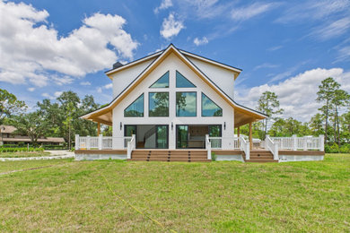 Large cottage white two-story stucco exterior home idea in Other with a metal roof and a black roof