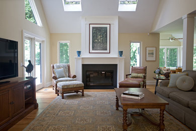 Example of a mid-sized transitional open concept light wood floor and brown floor living room design in New York with beige walls, a standard fireplace, a wood fireplace surround and a tv stand