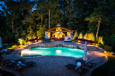 Photo of a large modern backyard custom-shaped pool in Atlanta with a pool house and brick pavers.