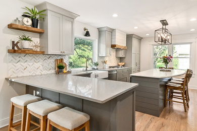 Inspiration for a huge farmhouse l-shaped medium tone wood floor and brown floor eat-in kitchen remodel in Milwaukee with a farmhouse sink, shaker cabinets, gray cabinets, quartz countertops, white backsplash, marble backsplash, stainless steel appliances, an island and gray countertops