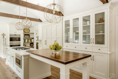 Inspiration for a large cottage u-shaped medium tone wood floor kitchen remodel in New York with shaker cabinets, white cabinets, quartz countertops, stainless steel appliances, a farmhouse sink and an island