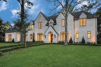 Large traditional beige two-story stone exterior home idea in Houston with a shingle roof