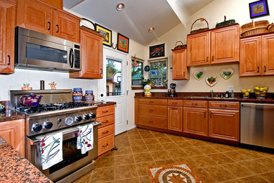 Kitchen - mid-sized transitional u-shaped ceramic tile and beige floor kitchen idea in Los Angeles with raised-panel cabinets, medium tone wood cabinets, granite countertops, stainless steel appliances and no island
