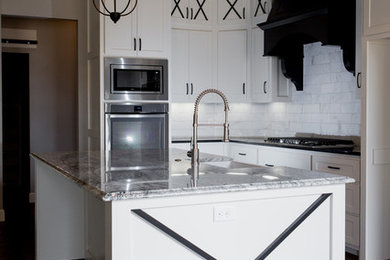 Inspiration for a transitional medium tone wood floor eat-in kitchen remodel in Oklahoma City with a farmhouse sink, shaker cabinets, white cabinets, granite countertops, white backsplash, stainless steel appliances and an island