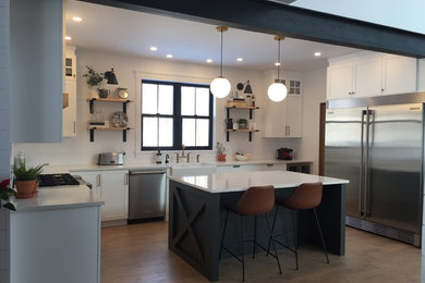 Inspiration for a large contemporary kitchen remodel in Ottawa with a farmhouse sink, shaker cabinets, white cabinets, quartz countertops, white backsplash, stainless steel appliances, an island and white countertops