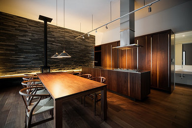 Modelo de cocina moderna abierta con fregadero integrado, armarios con paneles lisos, puertas de armario negras, encimera de acero inoxidable y una isla