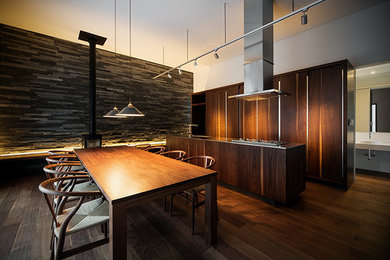 Modern open plan kitchen in Osaka with an integrated sink, flat-panel cabinets, black cabinets, stainless steel worktops and an island.