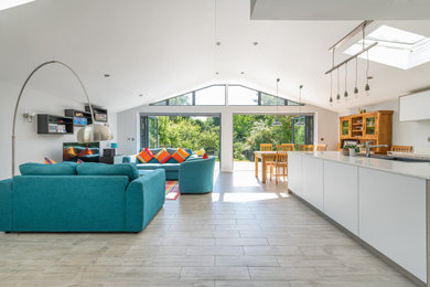 Inspiration for a contemporary grey and white open plan living room in Essex with white walls, porcelain flooring, a freestanding tv, grey floors and a vaulted ceiling.