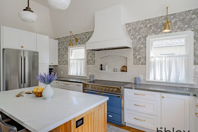 Example of a mid-sized transitional medium tone wood floor, brown floor and vaulted ceiling kitchen design in Orange County with ceramic backsplash, colored appliances, an island and gray countertops