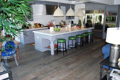 Example of a large l-shaped dark wood floor open concept kitchen design in Phoenix with a farmhouse sink, white backsplash, stainless steel appliances and an island