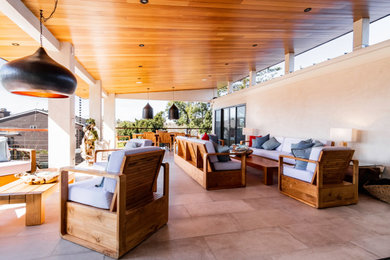 Example of a large minimalist deck design in San Diego with a roof extension