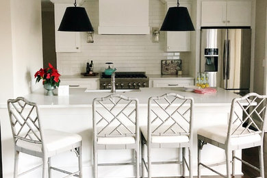Mid-sized transitional galley dark wood floor and brown floor eat-in kitchen photo in Atlanta with a farmhouse sink, shaker cabinets, white cabinets, solid surface countertops, white backsplash, subway tile backsplash, stainless steel appliances, an island and white countertops