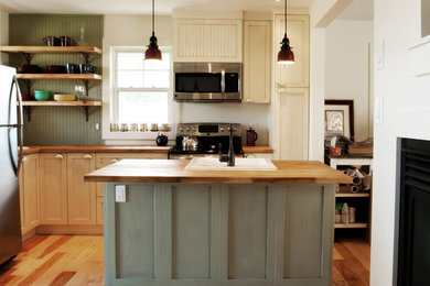 Inspiration for a small coastal l-shaped medium tone wood floor open concept kitchen remodel in Toronto with a drop-in sink, recessed-panel cabinets, light wood cabinets, wood countertops, stainless steel appliances and an island