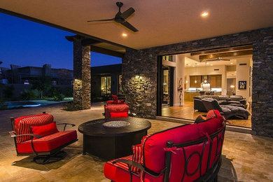 Photo of a large contemporary backyard patio in Phoenix with a fire feature, natural stone pavers and a roof extension.