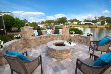 Photo of a mid-sized traditional backyard patio in Tampa with a fire feature, brick pavers and no cover.