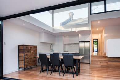 This is an example of a large contemporary open plan dining in Sydney with white walls, medium hardwood floors and brown floor.