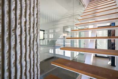 Ejemplo de escalera recta contemporánea de tamaño medio sin contrahuella con escalones de madera y barandilla de metal