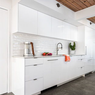 На фото: с высоким бюджетом маленькие параллельные кухни в стиле ретро с обеденным столом, одинарной раковиной, плоскими фасадами, белыми фасадами, столешницей из кварцевого композита, белым фартуком, фартуком из керамической плитки, техникой под мебельный фасад, бетонным полом и островом