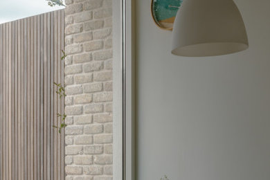 Design ideas for a contemporary open plan kitchen in Dublin with a built-in sink, flat-panel cabinets, light wood cabinets, limestone worktops, stainless steel appliances, cement flooring, no island, grey floors, grey worktops and exposed beams.