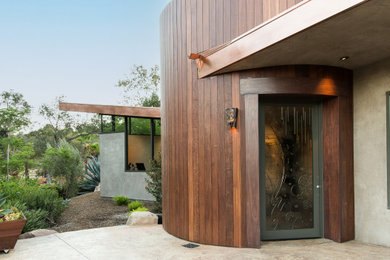 Large trendy gray one-story wood house exterior photo in Los Angeles with a butterfly roof and a metal roof