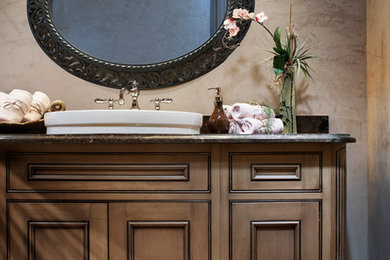 Mid-sized elegant porcelain tile and brown floor bathroom photo in Portland with recessed-panel cabinets, dark wood cabinets, brown walls and a drop-in sink