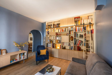Cette image montre un grand salon design fermé avec une bibliothèque ou un coin lecture, un mur bleu, un sol en bois brun et un sol marron.