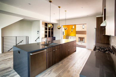 Open concept kitchen - contemporary galley light wood floor open concept kitchen idea in Los Angeles with an undermount sink, flat-panel cabinets, dark wood cabinets, quartzite countertops, beige backsplash, porcelain backsplash, stainless steel appliances and an island