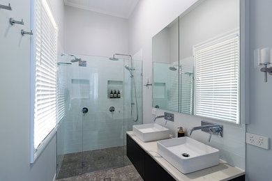 Mid-sized modern master wet room bathroom in Brisbane with furniture-like cabinets, dark wood cabinets, subway tile, grey walls, terrazzo floors, a console sink, quartzite benchtops, multi-coloured floor and white benchtops.