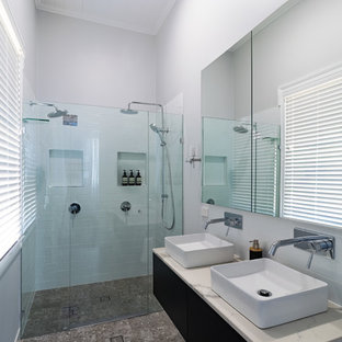 Cette image montre une salle de bain principale minimaliste de taille moyenne avec un placard en trompe-l'oeil, des portes de placard en bois sombre, un espace douche bain, un carrelage métro, un mur gris, sol en terrazzo, un plan vasque, un plan de toilette en quartz, un sol multicolore et un plan de toilette blanc.