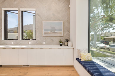 Inspiration for a mid-sized contemporary single-wall light wood floor eat-in kitchen remodel in Los Angeles with a single-bowl sink, flat-panel cabinets, white cabinets, quartz countertops, gray backsplash, porcelain backsplash, stainless steel appliances, white countertops and an island
