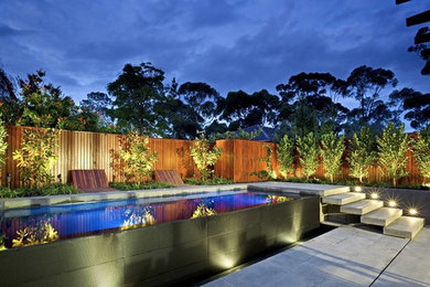 Design ideas for a mid-sized contemporary backyard partial sun formal garden in Melbourne with a water feature and natural stone pavers.