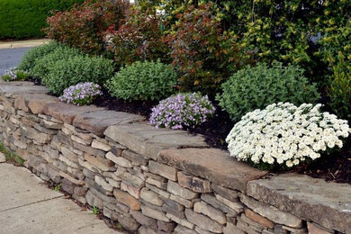 Design ideas for a mid-sized contemporary front yard partial sun garden for spring in New York with a retaining wall and concrete pavers.
