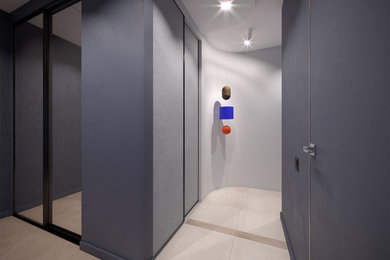 Imagen de hall contemporáneo pequeño con paredes azules, suelo de baldosas de porcelana, puerta simple, puerta de madera clara y suelo beige