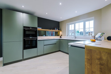 This is an example of a medium sized contemporary u-shaped kitchen in Manchester with a built-in sink, blue cabinets and porcelain flooring.