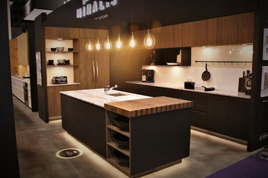 Open concept kitchen - large contemporary u-shaped gray floor open concept kitchen idea in Other with an undermount sink, flat-panel cabinets, black cabinets, granite countertops, white backsplash, stone slab backsplash, paneled appliances and an island
