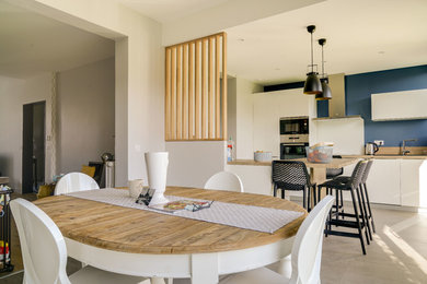 Cette image montre une grande salle à manger ouverte sur le salon design avec un mur bleu, un sol en carrelage de céramique, aucune cheminée et un sol gris.